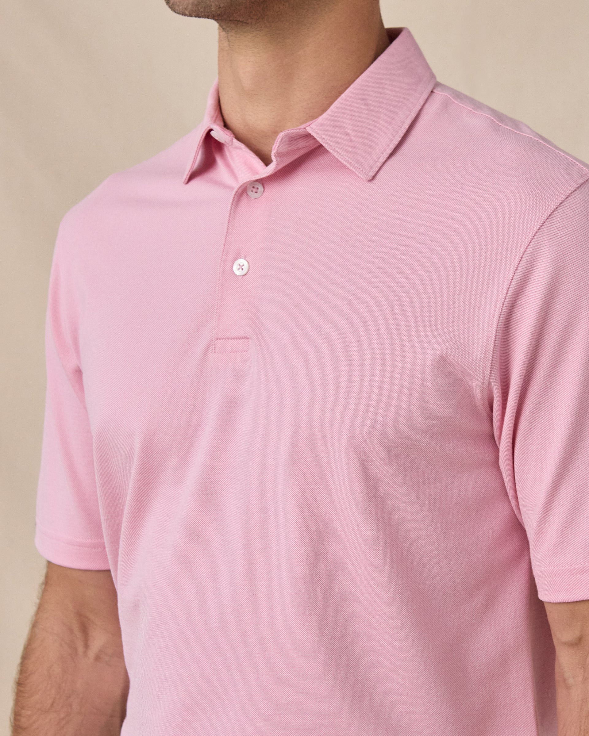 Close-up side view of the Oxford Polo in punch pink highlighting the textured knit fabric and tailored fit