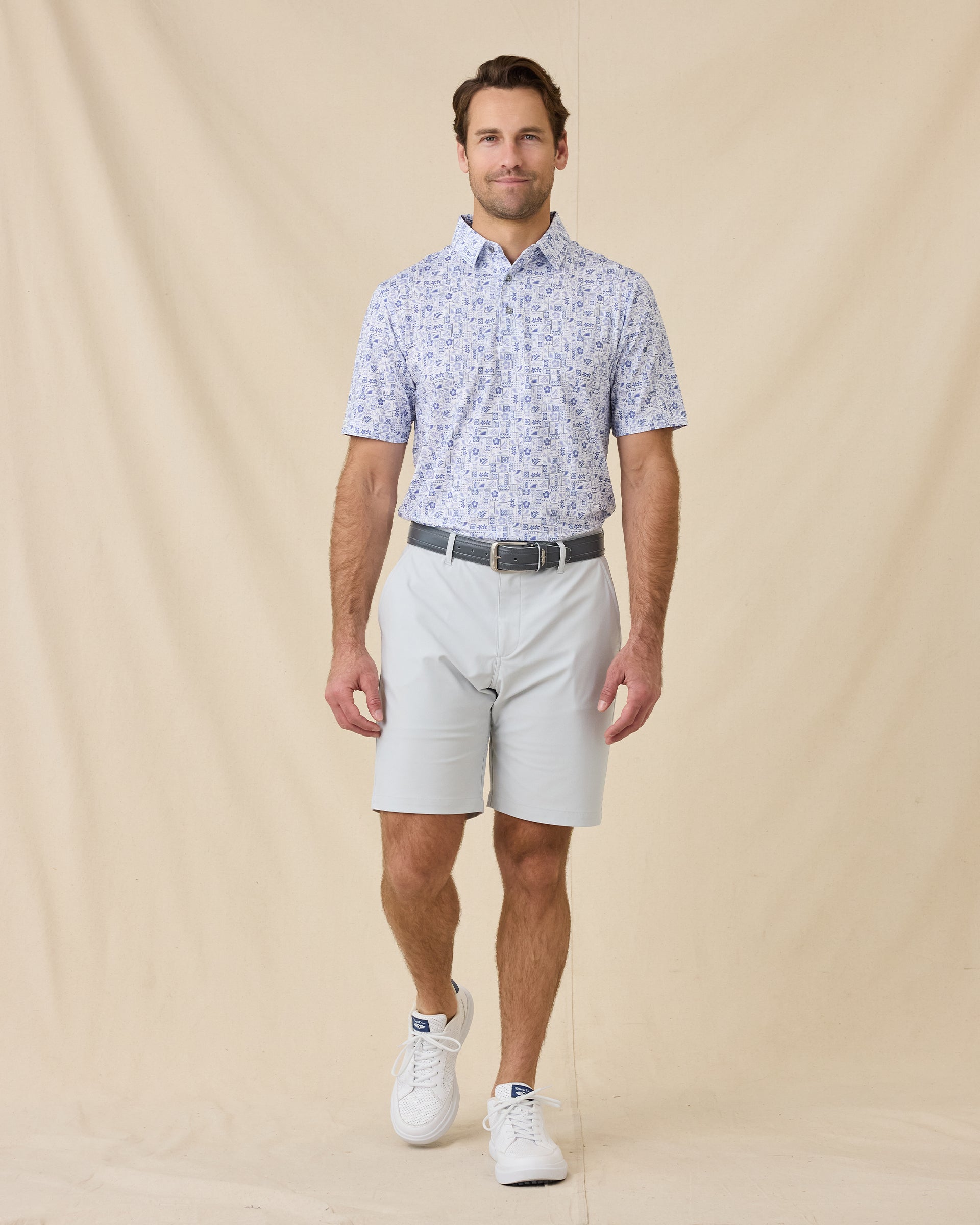 Model wearing the Waterman Polo in Tidal Blue paired with light gray golf shorts, full outfit