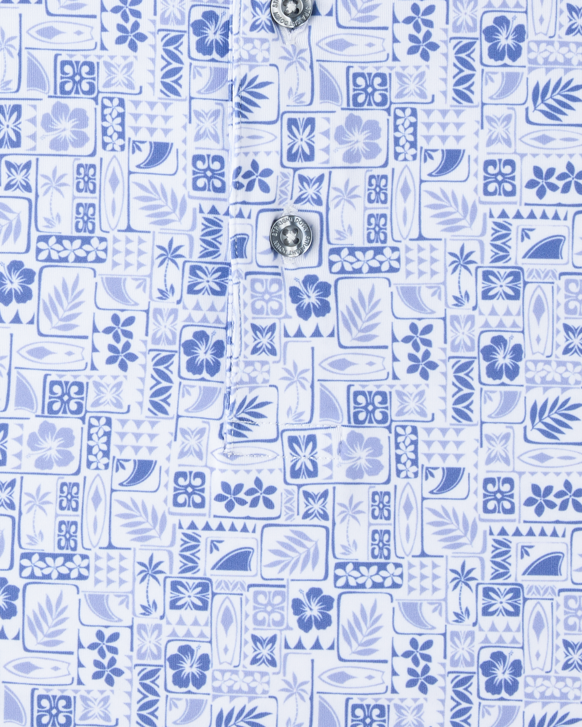 Close-up of the Waterman Polo in Tidal Blue featuring an intricate tile pattern with tropical florals, palm fronds, and surf-inspired details