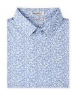 Close-up product view of the Tropics Lounge Polo in Blue Shade, featuring an allover white botanical print on a light blue background and a three-button placket.