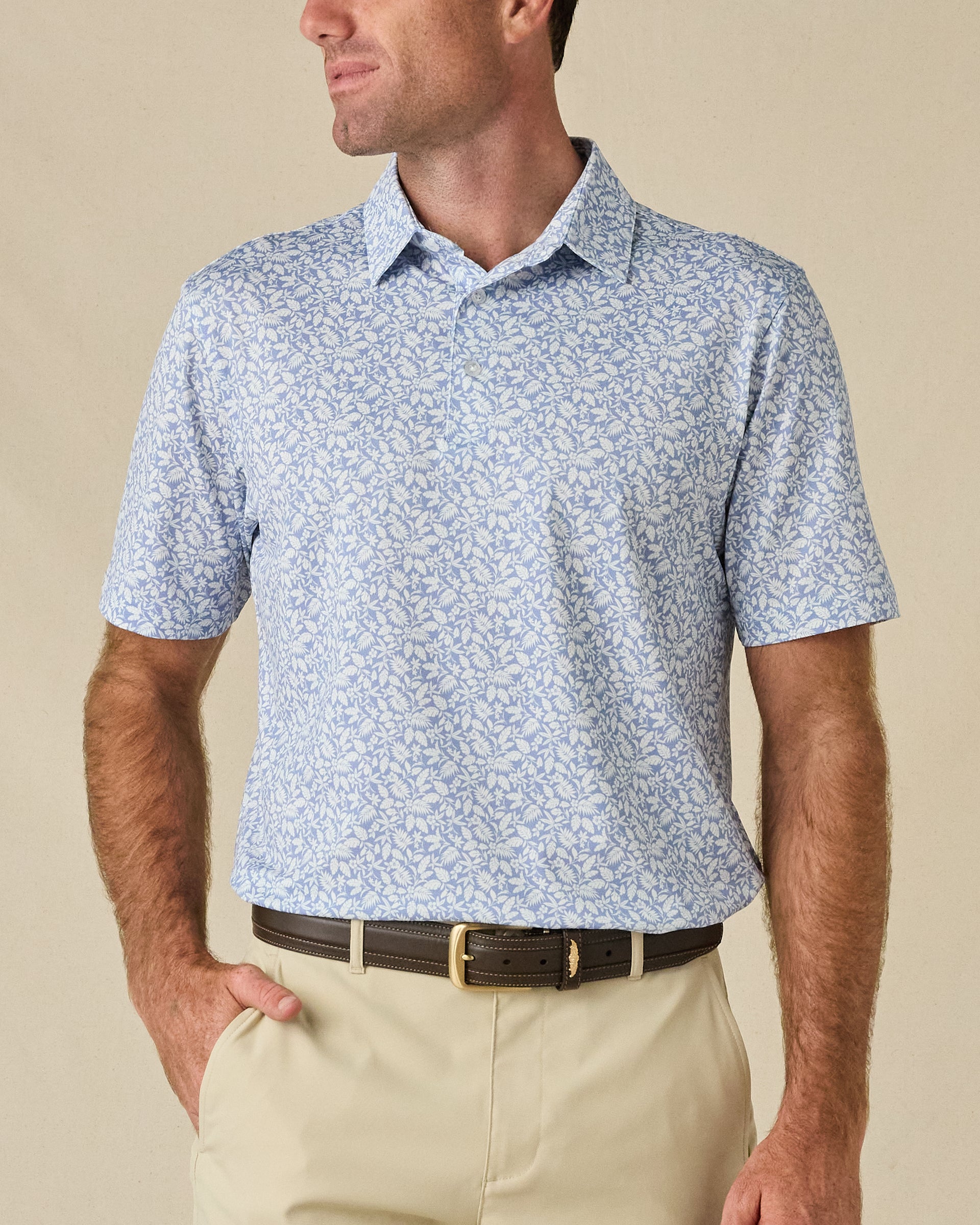 Model wearing the Tropics Lounge Polo in Blue Shade, featuring an all-over tonal botanical print and classic polo collar.