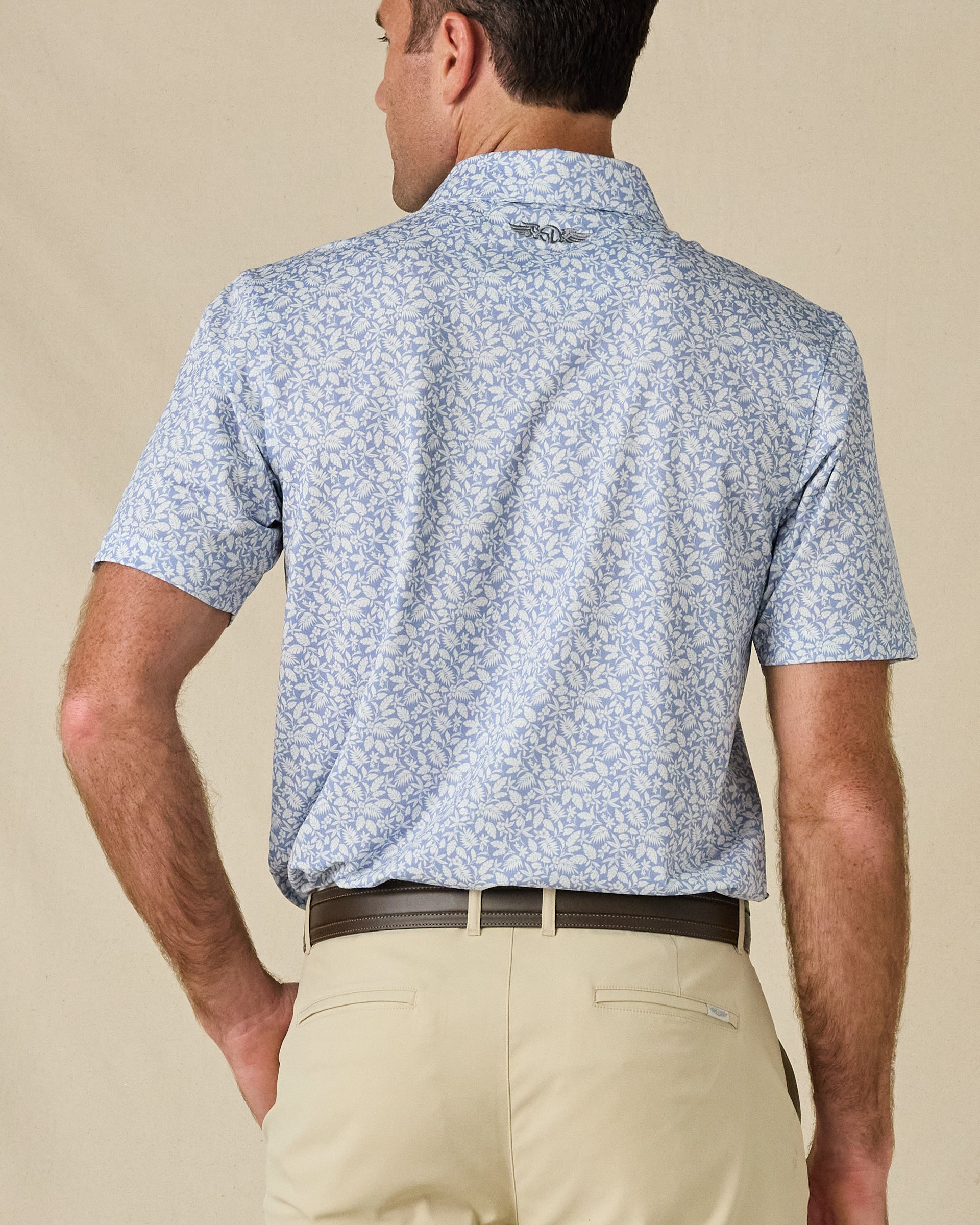 Back view of the Tropics Lounge Polo in Blue Shade, highlighting the botanical print and embroidered logo below the collar.
