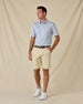 Model wearing the Tropics Lounge Polo in Blue Shade with khaki golf shorts, a brown belt, and white sneakers.