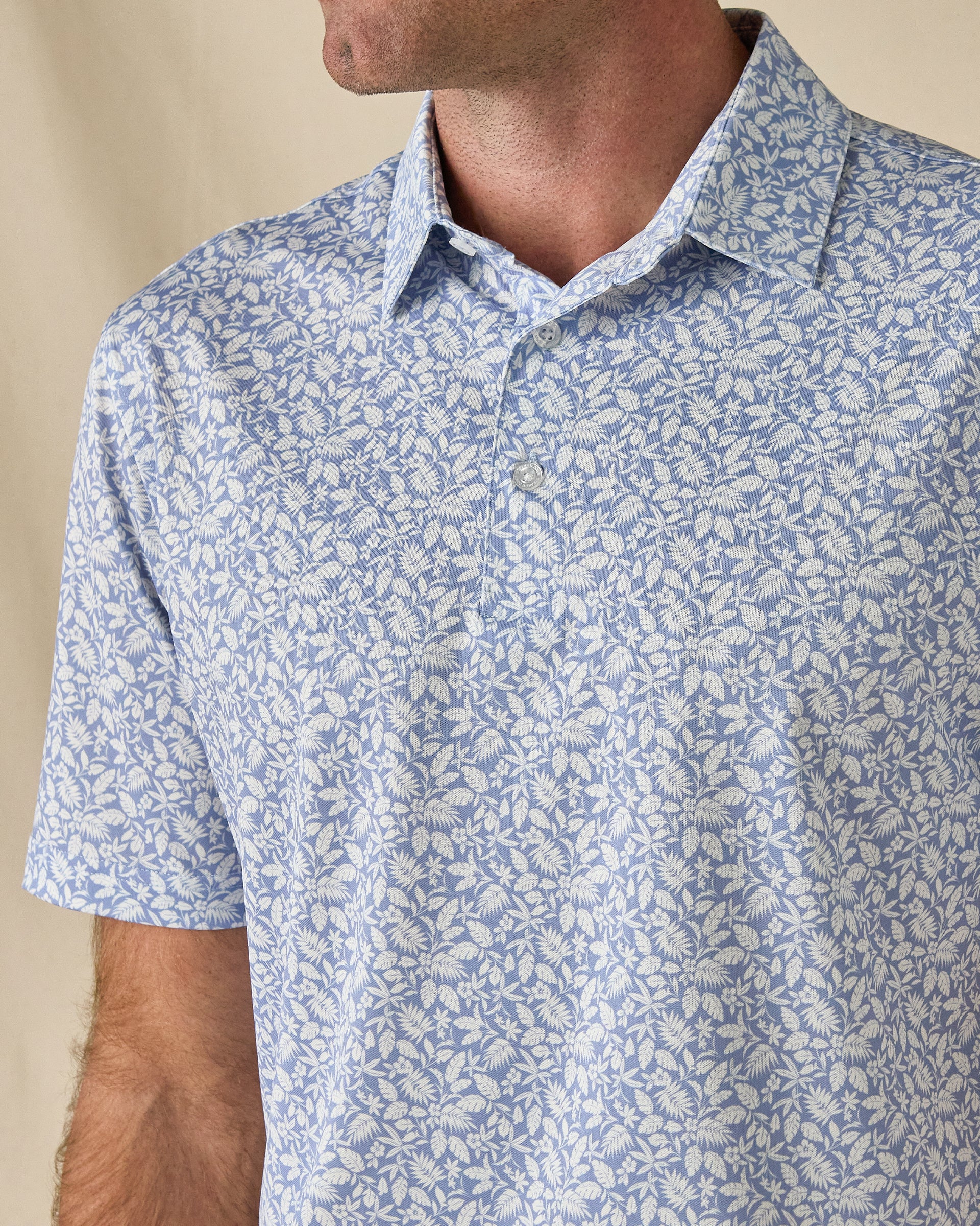 Close-up of the Tropics Lounge Polo in Blue Shade, highlighting the intricate botanical print, collar, and button placket.