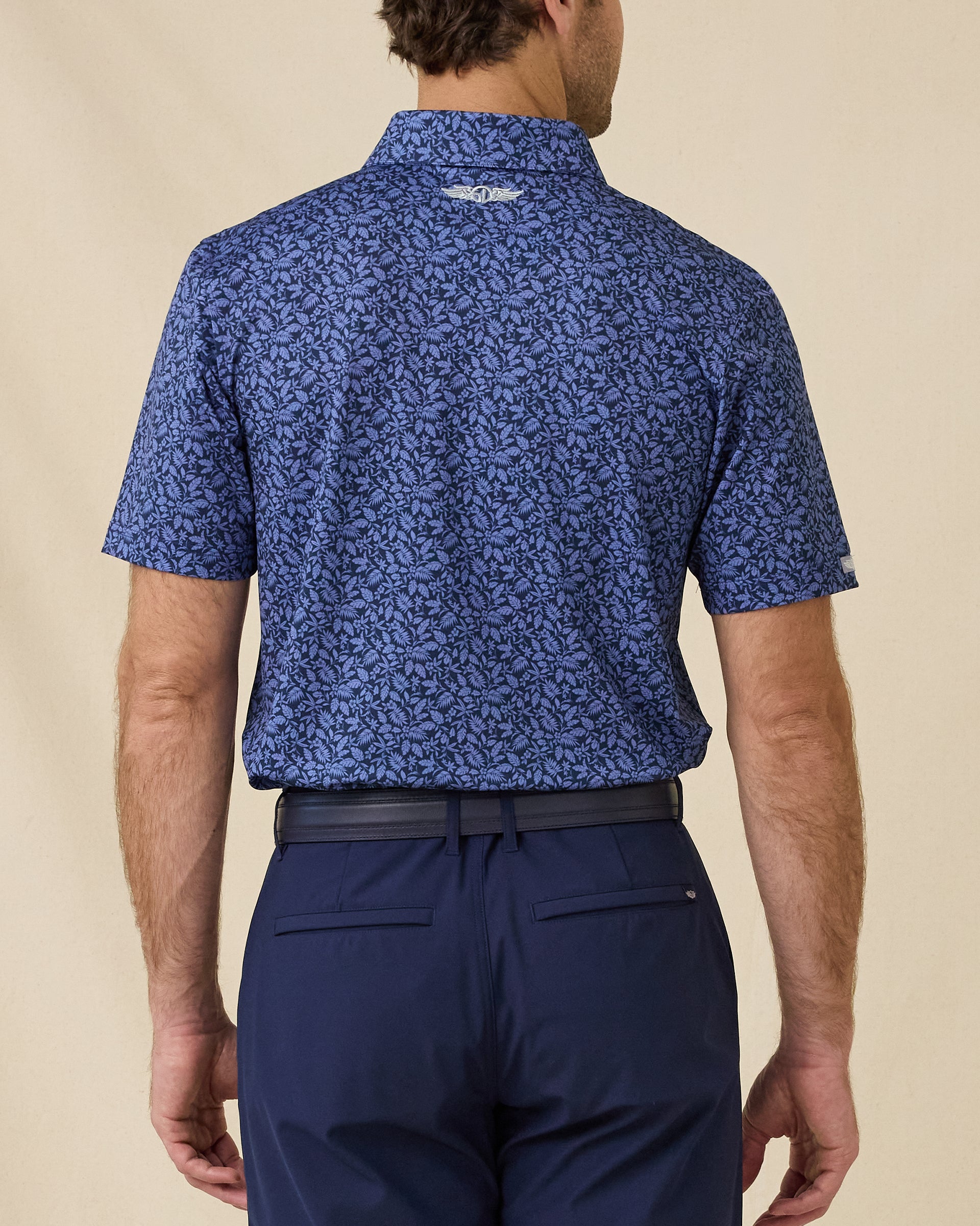 Back view of the Tropics Lounge Polo in Tidal Blue featuring a full-coverage tropical print