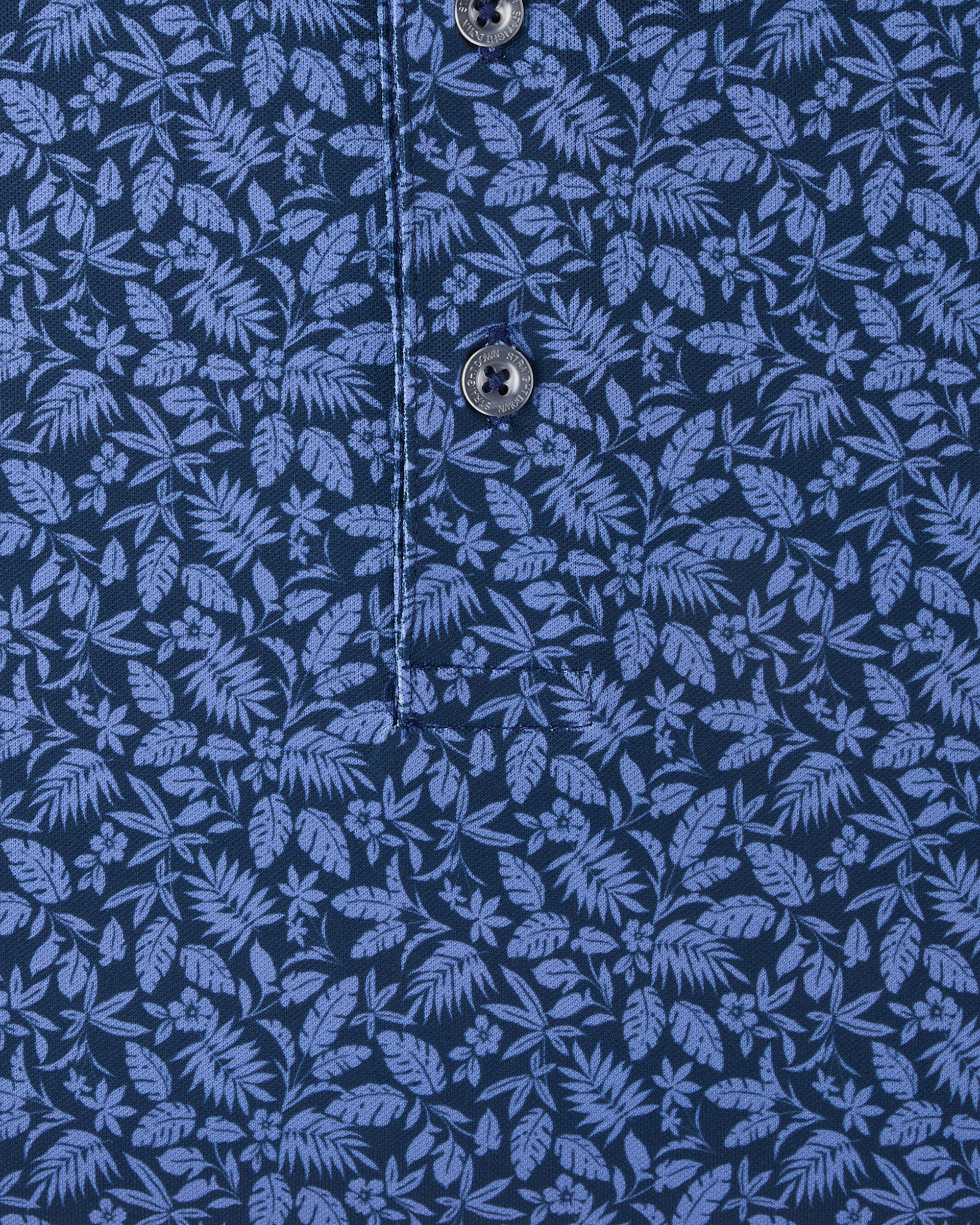 Close-up of the Tropics Lounge Polo in Tidal Blue highlighting the detailed tropical print in contrasting blue tones