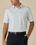 Model wearing the 29 Palms Polo in Herb, featuring a subtle all-over palm tree print in soft green tones.