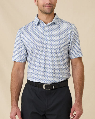 Model wearing the Day of the Dead Polo in Herb with black golf pants, showing the all-over sugar skull print.