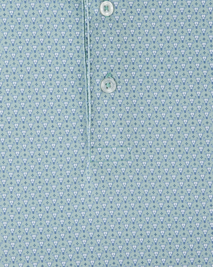 Close-up of a soft blue-green and white patterned button-down shirt fabric, showing a repeating cattle skull print and two white buttons on the placket.