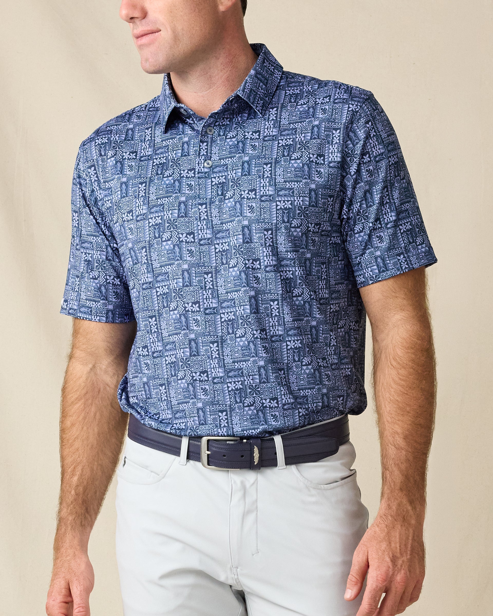 Model wearing the Reef Runner Polo in Blue Shade, featuring an allover geometric patchwork print in layered blue tones.
