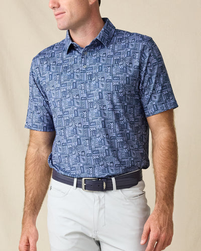 Model wearing the Reef Runner Polo in Blue Shade, featuring an allover geometric patchwork print in layered blue tones.