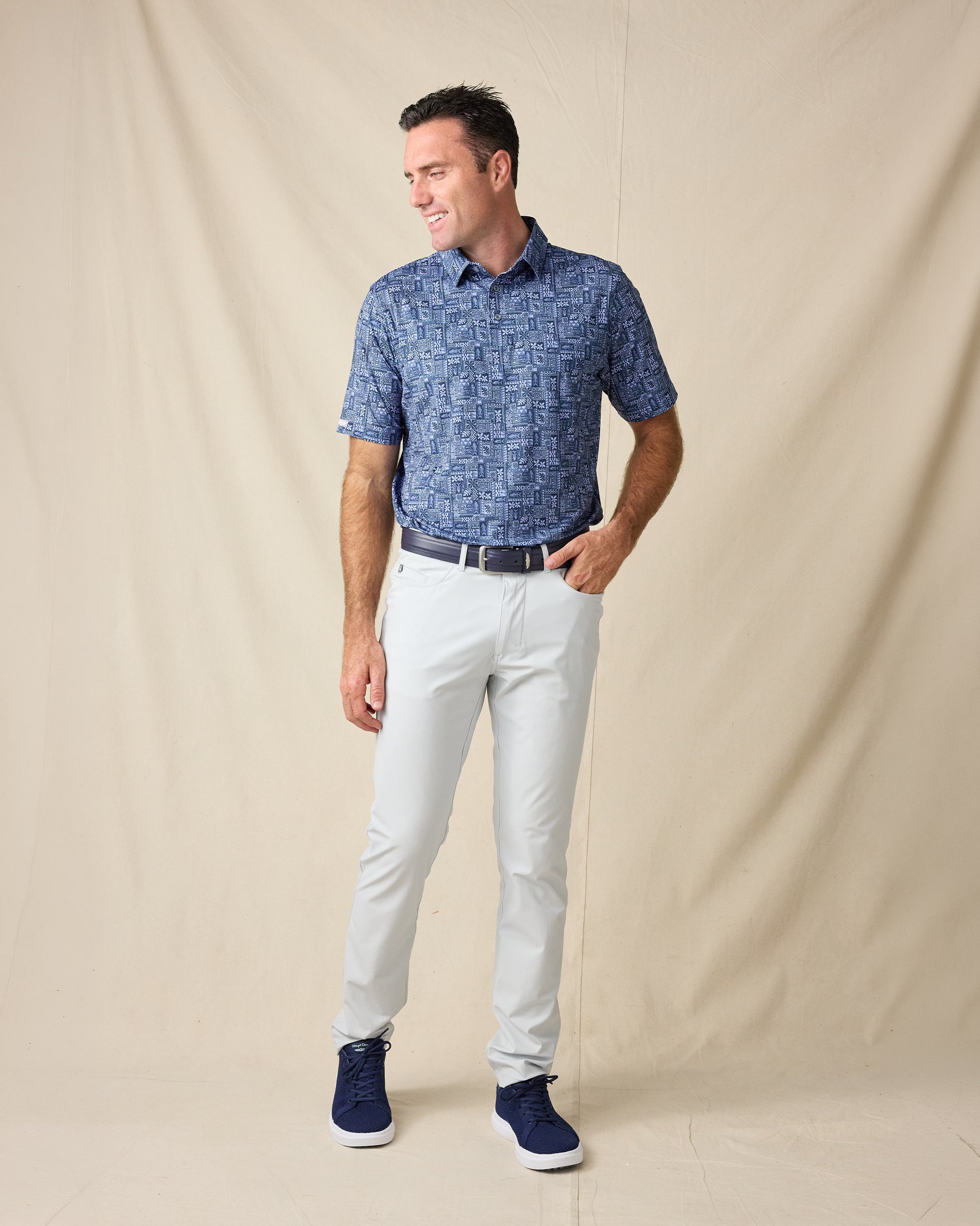 Model wearing the Reef Runner Polo in Blue Shade with light gray pants, a navy belt, and navy sneakers.