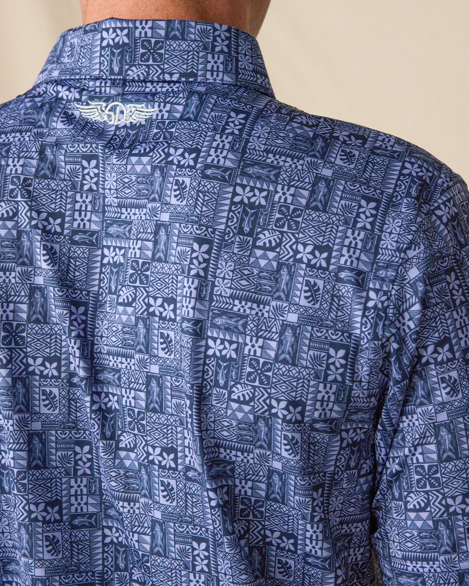 Close-up of the Reef Runner Polo in Blue Shade, featuring an all-over geometric print and embroidered Straight Down logo below the back collar.