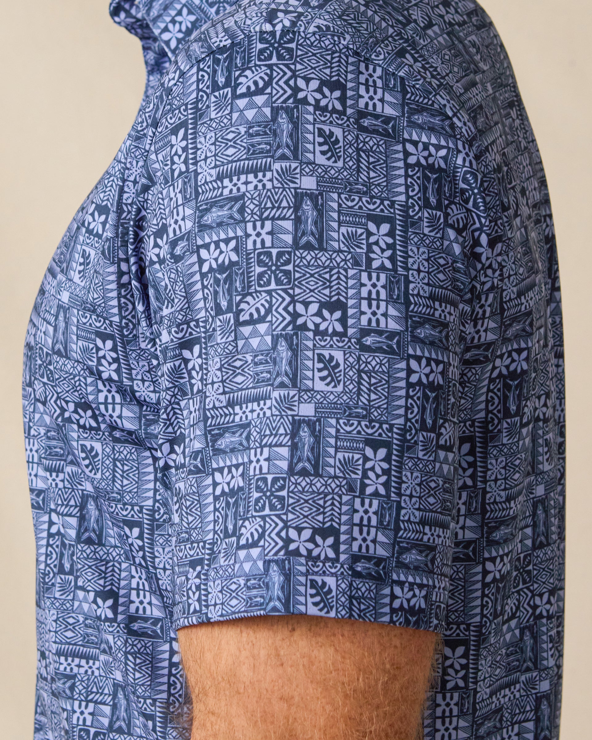 Close-up of the Reef Runner Polo in Blue Shade, highlighting the intricate geometric and botanical-inspired pattern across the sleeve and body.