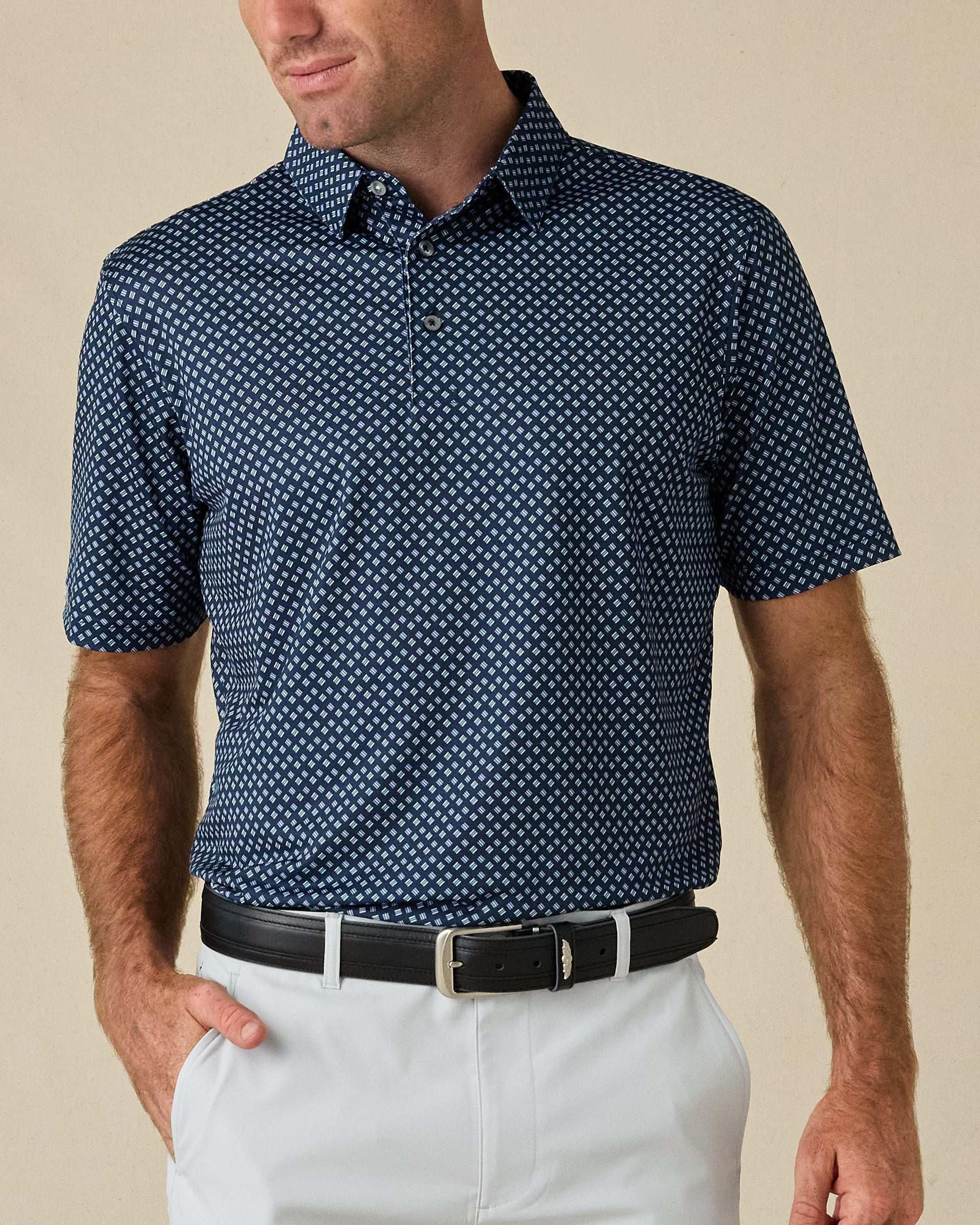 Model wearing the Banksville Polo in New Indigo with white golf pants and a black belt.