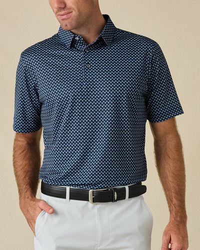 Model wearing the Banksville Polo in New Indigo with white golf pants and a black belt.