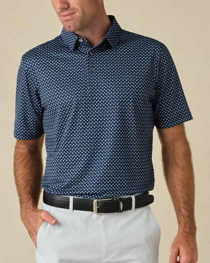 Model wearing the Banksville Polo in New Indigo with white golf pants and a black belt.
