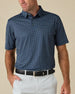 Model wearing the Banksville Polo in New Indigo with white golf pants and a black belt.