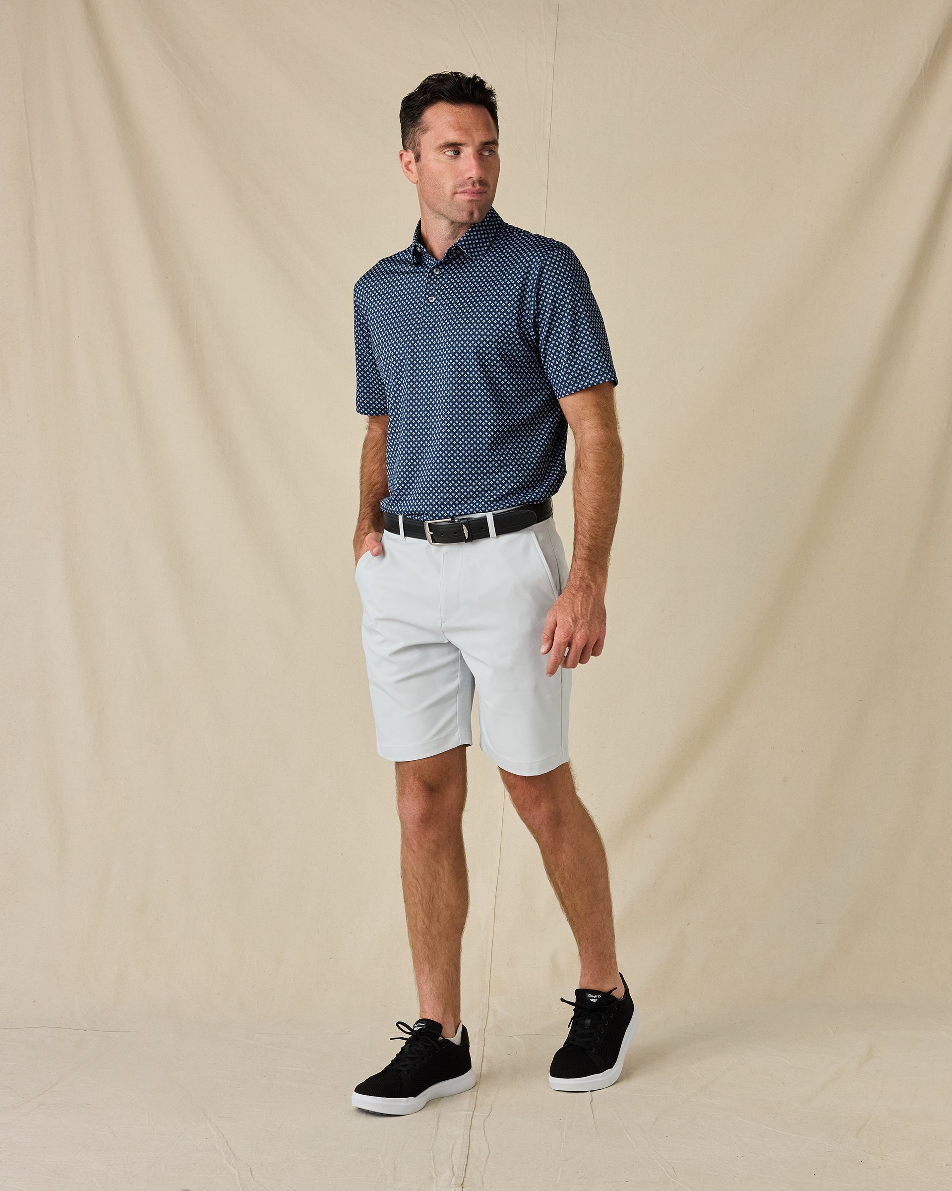 Model wearing the Banksville Polo in New Indigo with white golf shorts and black sneakers.