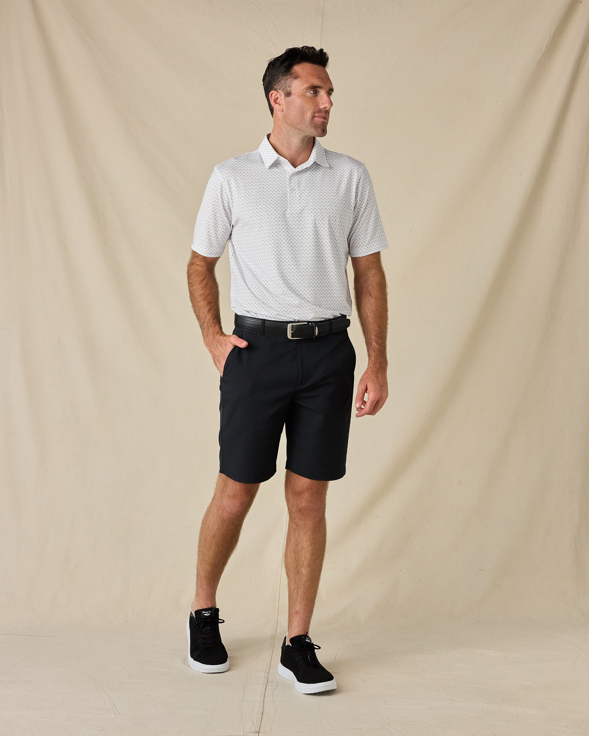 Model wearing the Brookhurst Polo in Herb with black shorts, a black belt, and black sneakers.