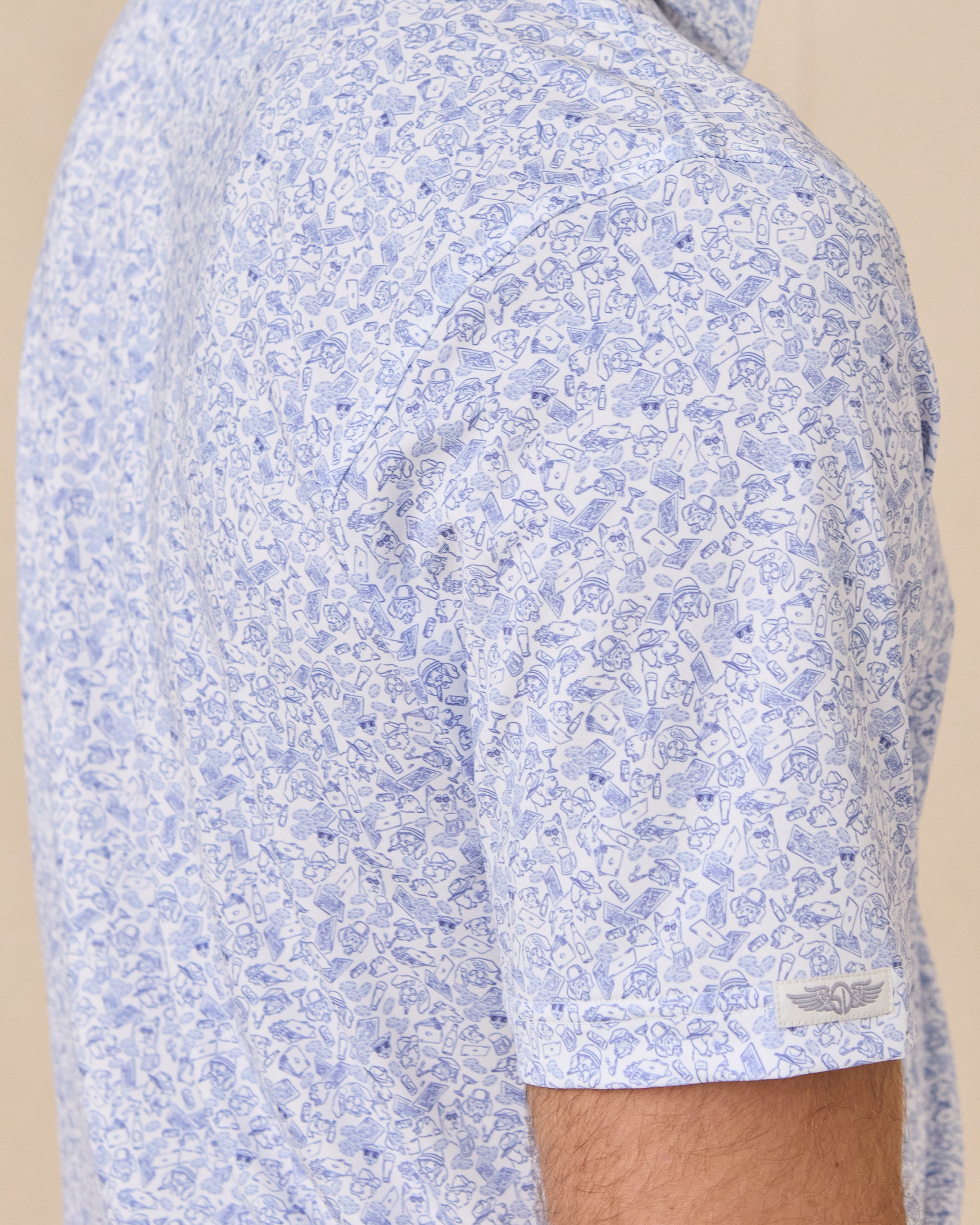 Sleeve detail of the Poker Dawgs Polo in Tidal Blue showing the allover poker-themed dog print and Straight Down logo patch