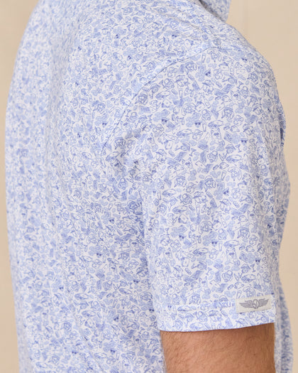 Sleeve detail of the Poker Dawgs Polo in Tidal Blue showing the allover poker-themed dog print and Straight Down logo patch