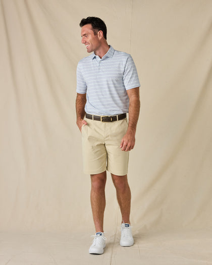 Model wearing the Oceano Dunes Striped Polo in Blue Shade with khaki golf shorts, a brown belt, and white sneakers.