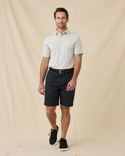 Full-length view of model wearing the Oceano Dunes Striped Polo in Cantaloupe with black shorts, a black belt, and black sneakers.