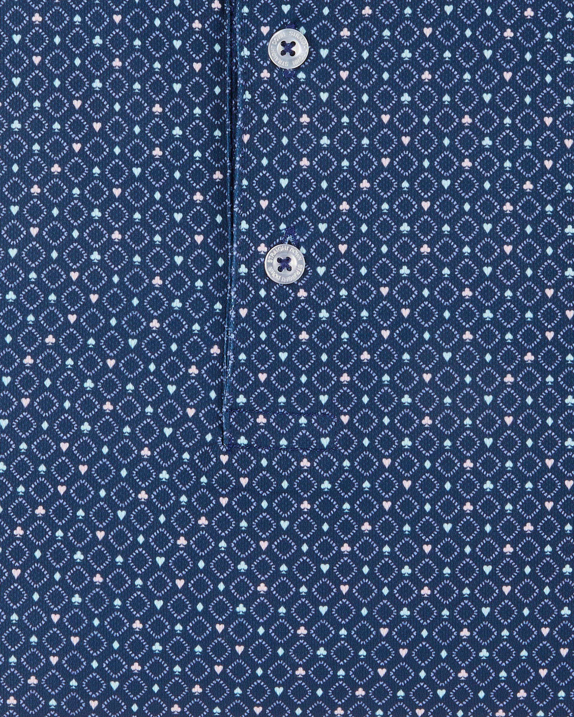 Detail view of the Casino Polo in Blue Shade showing the geometric pattern, small pastel playing card suit motifs, and branded buttons.