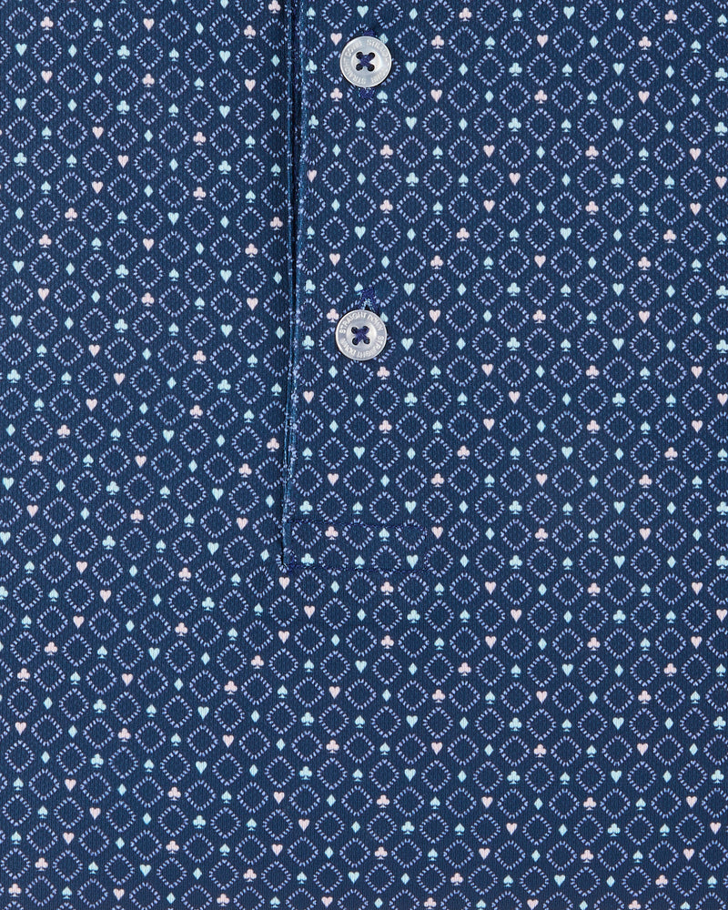 Detail view of the Casino Polo in Blue Shade showing the geometric pattern, small pastel playing card suit motifs, and branded buttons.