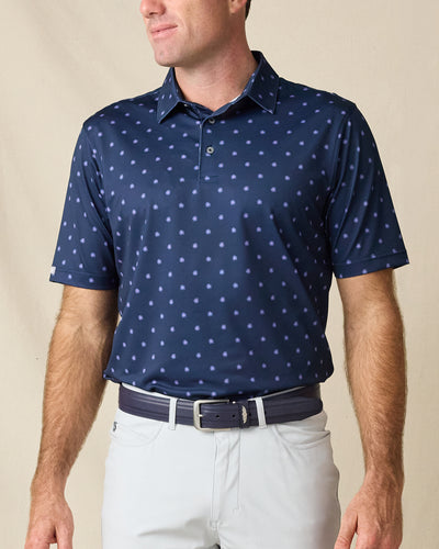Model wearing the Al Fresco Polo in New Indigo, featuring an allover light blue and lavender geometric print with a classic polo collar.