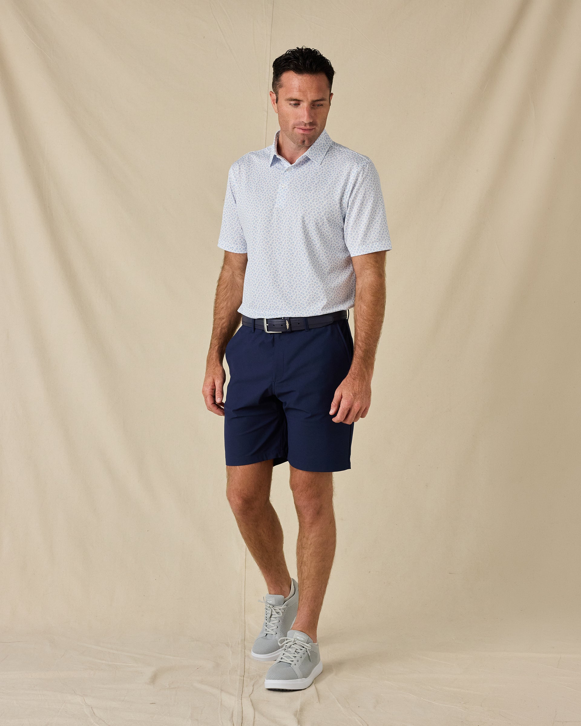 Model wearing the Hofbrau Polo in Blue Shade with navy golf shorts, a coordinating belt, and gray sneakers.