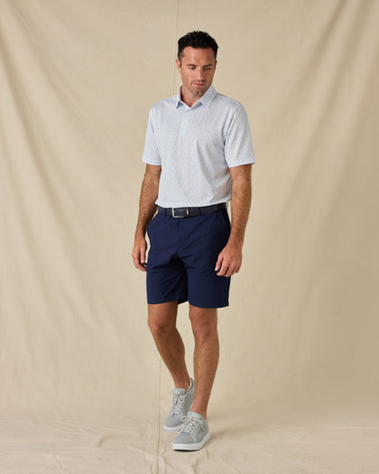 Model wearing the Hofbrau Polo in Blue Shade with navy golf shorts, a coordinating belt, and gray sneakers.