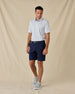 Model wearing the Hofbrau Polo in Blue Shade with navy golf shorts, a coordinating belt, and gray sneakers.