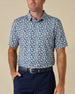 Model wearing the Point Reyes Polo in Mint Tea, featuring a dense floral print in light blue and soft pink against a navy background.