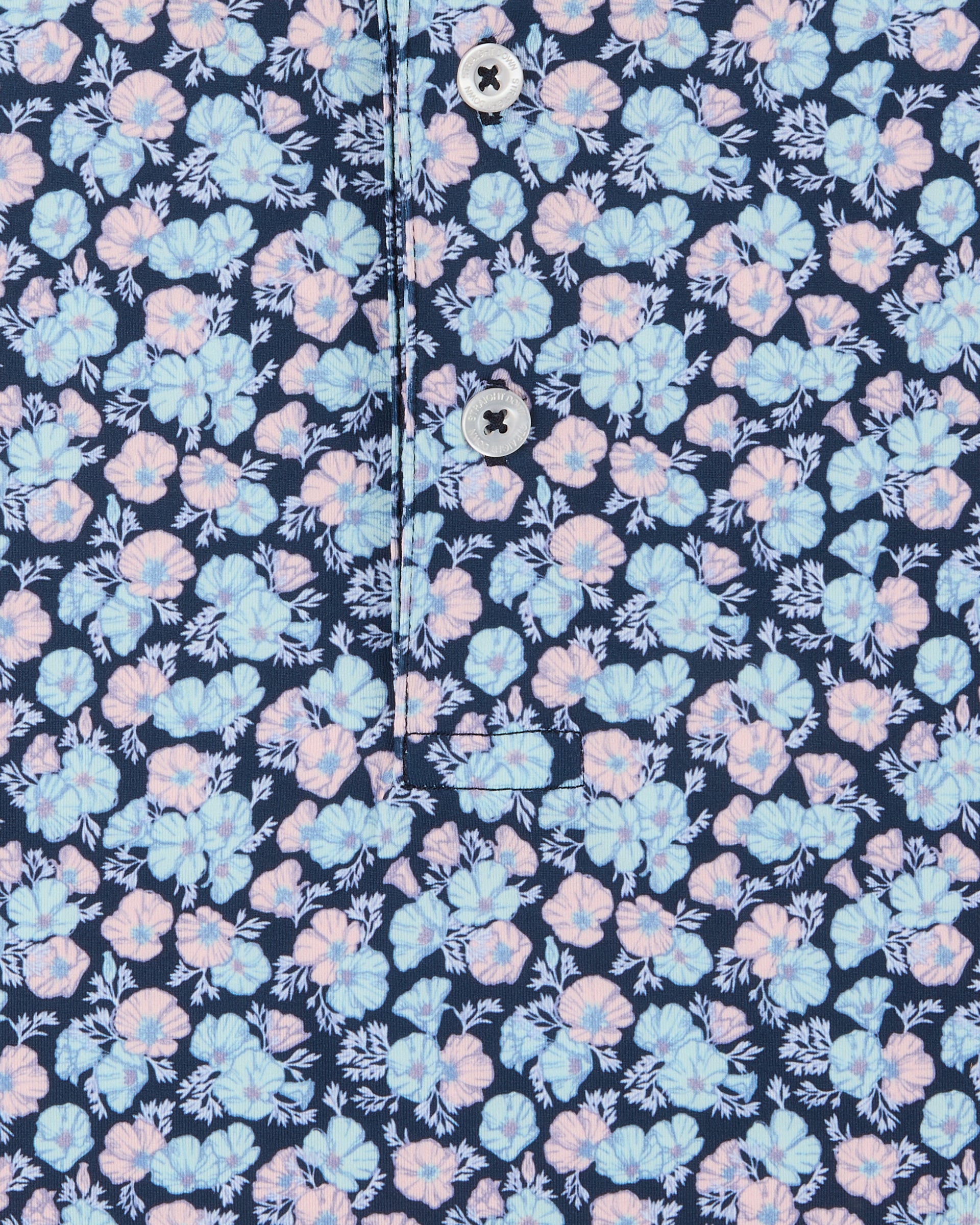 Close-up of a floral-patterned shirt fabric with a navy blue background, light blue and pink flowers, and two visible buttons on the placket.