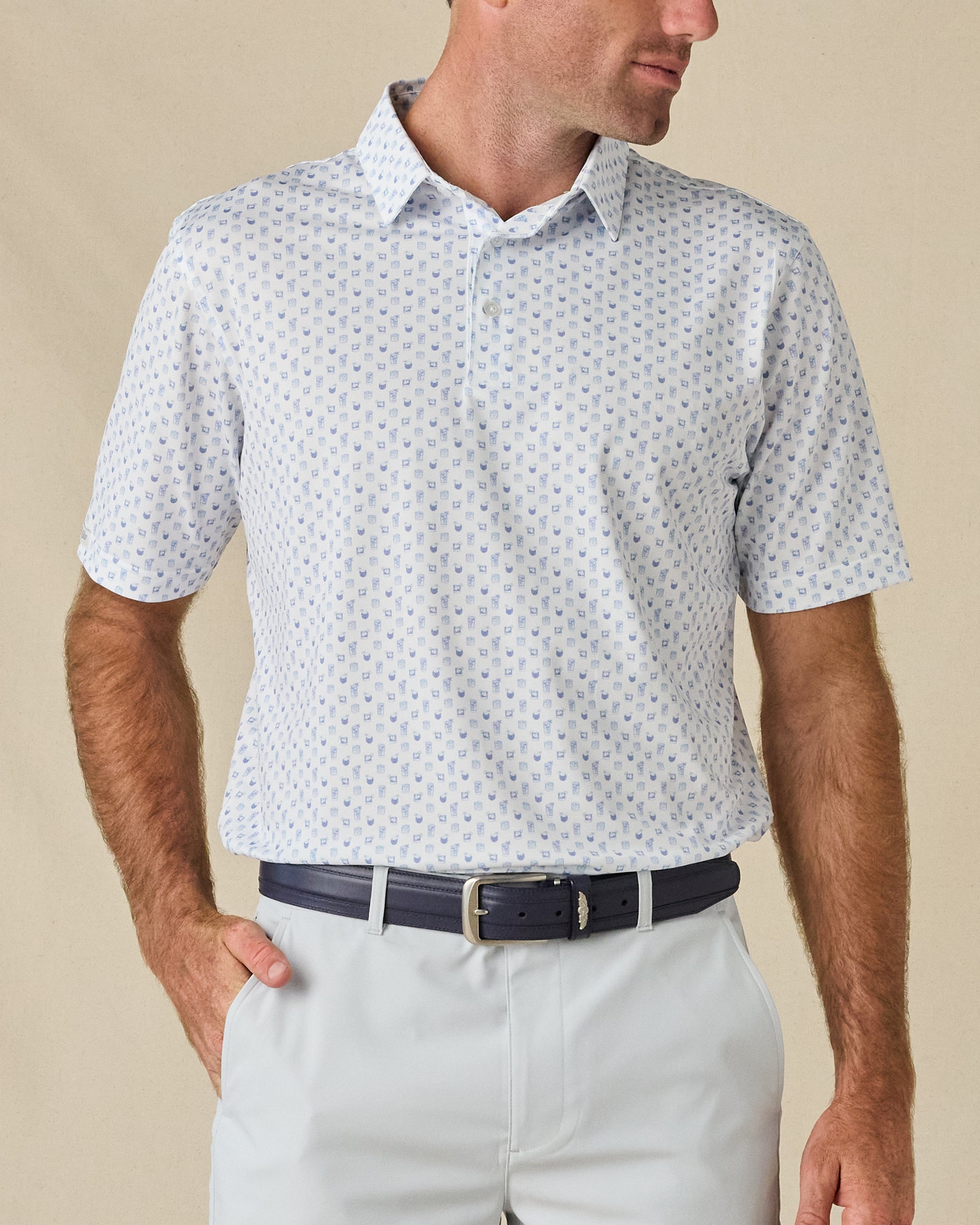 Model wearing the Trader Vics Polo in Blue Shade with an all-over light blue geometric print and light-colored golf shorts.