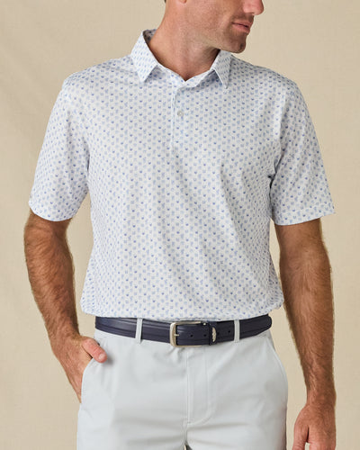 Model wearing the Trader Vics Polo in Blue Shade with an all-over light blue geometric print and light-colored golf shorts.