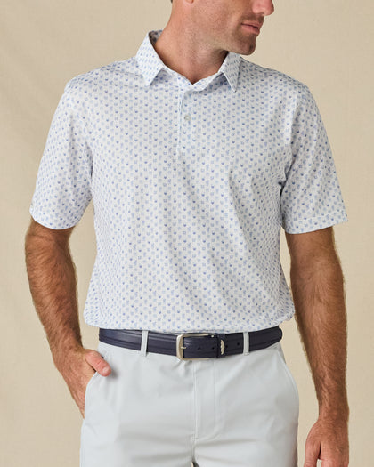 Model wearing the Trader Vics Polo in Blue Shade with an all-over light blue geometric print and light-colored golf shorts.