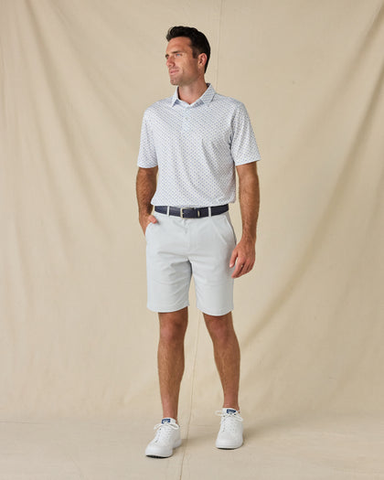 Model wearing the Trader Vics Polo in Blue Shade with light-colored golf shorts, a navy belt, and white sneakers.