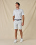 Model wearing the Trader Vics Polo in Blue Shade with light-colored golf shorts, a navy belt, and white sneakers.