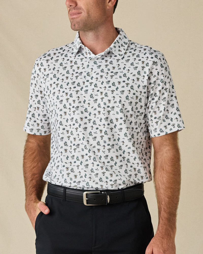 Model wearing the Siesta Polo in Herb, featuring an all-over Western-inspired print with cacti, desert motifs, and cowboy details.