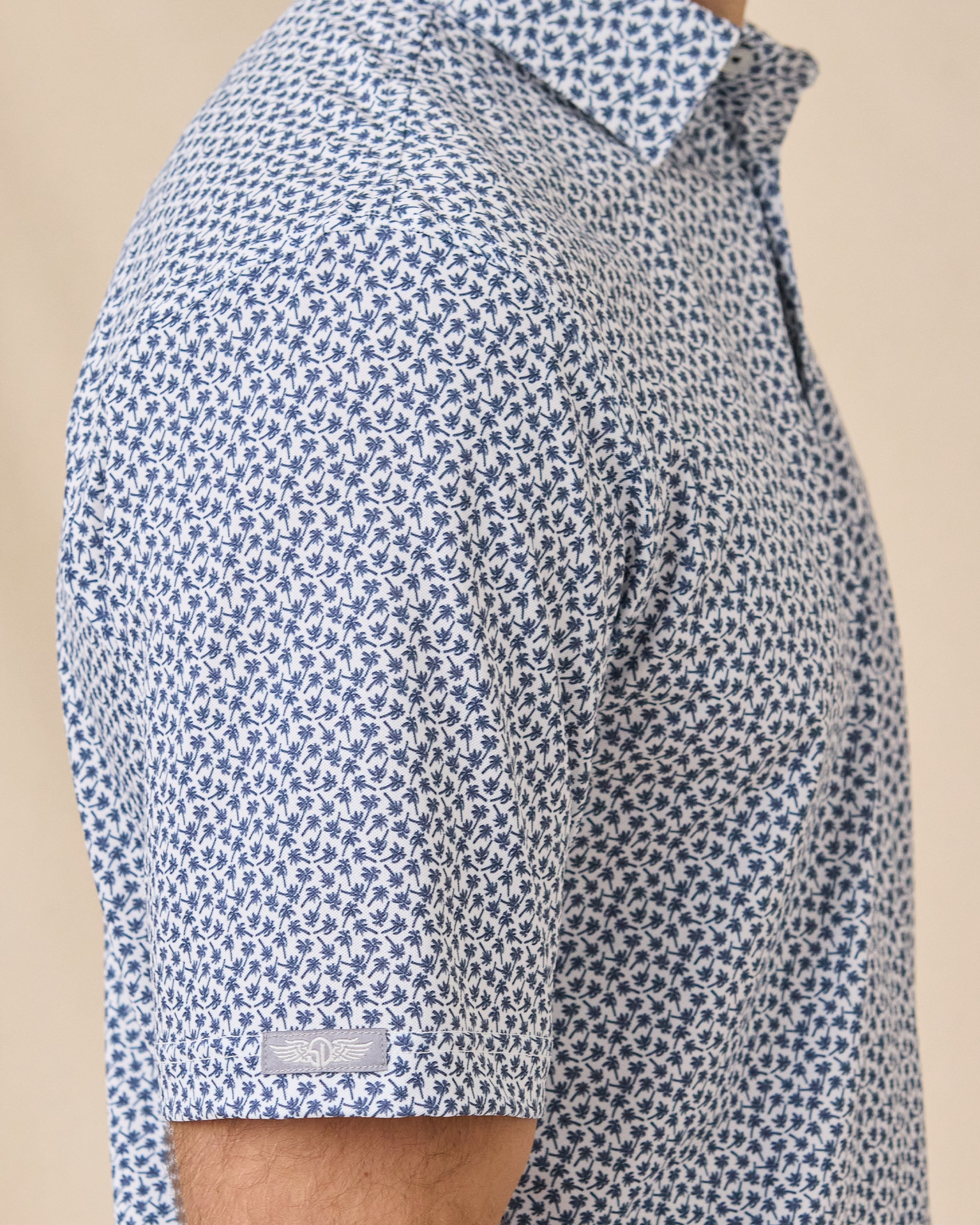 Sleeve detail of the Date Palm Polo in New Indigo highlighting the palm tree print and Straight Down logo tab