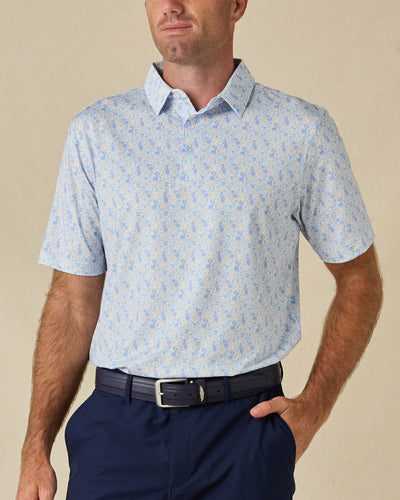 Model wearing the Pasadena Polo in Lake, featuring an all-over floral print in soft blue, lavender, and neutral tones.