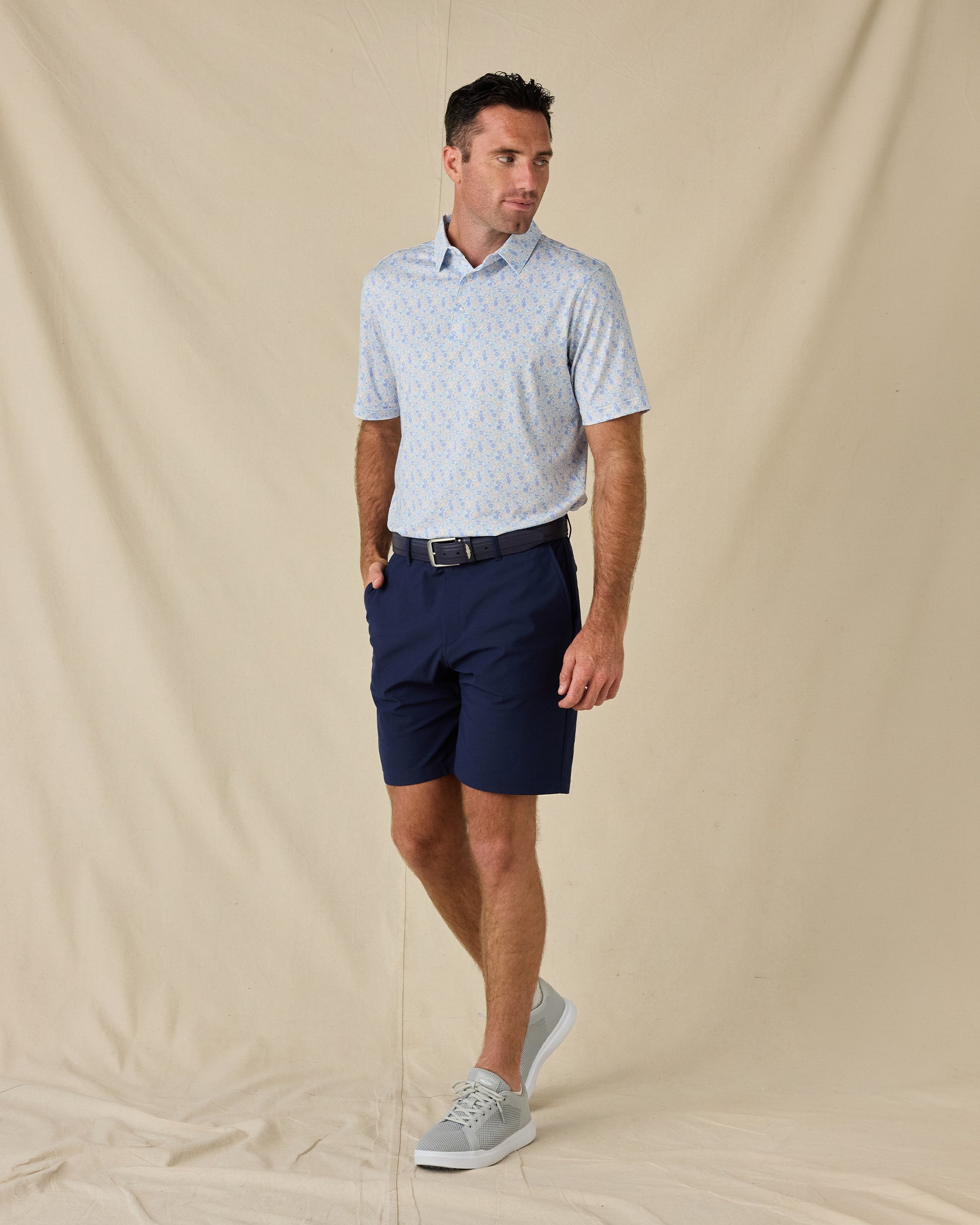 Model wearing the Pasadena Polo in Lake with navy golf shorts, a coordinating belt, and gray sneakers.