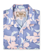 Folded blue short-sleeve shirt with a pink floral print, pearl snap buttons and dual chest pockets.
