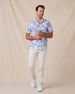 Man wearing a blue floral short-sleeve shirt with off-white pants and white sneakers.