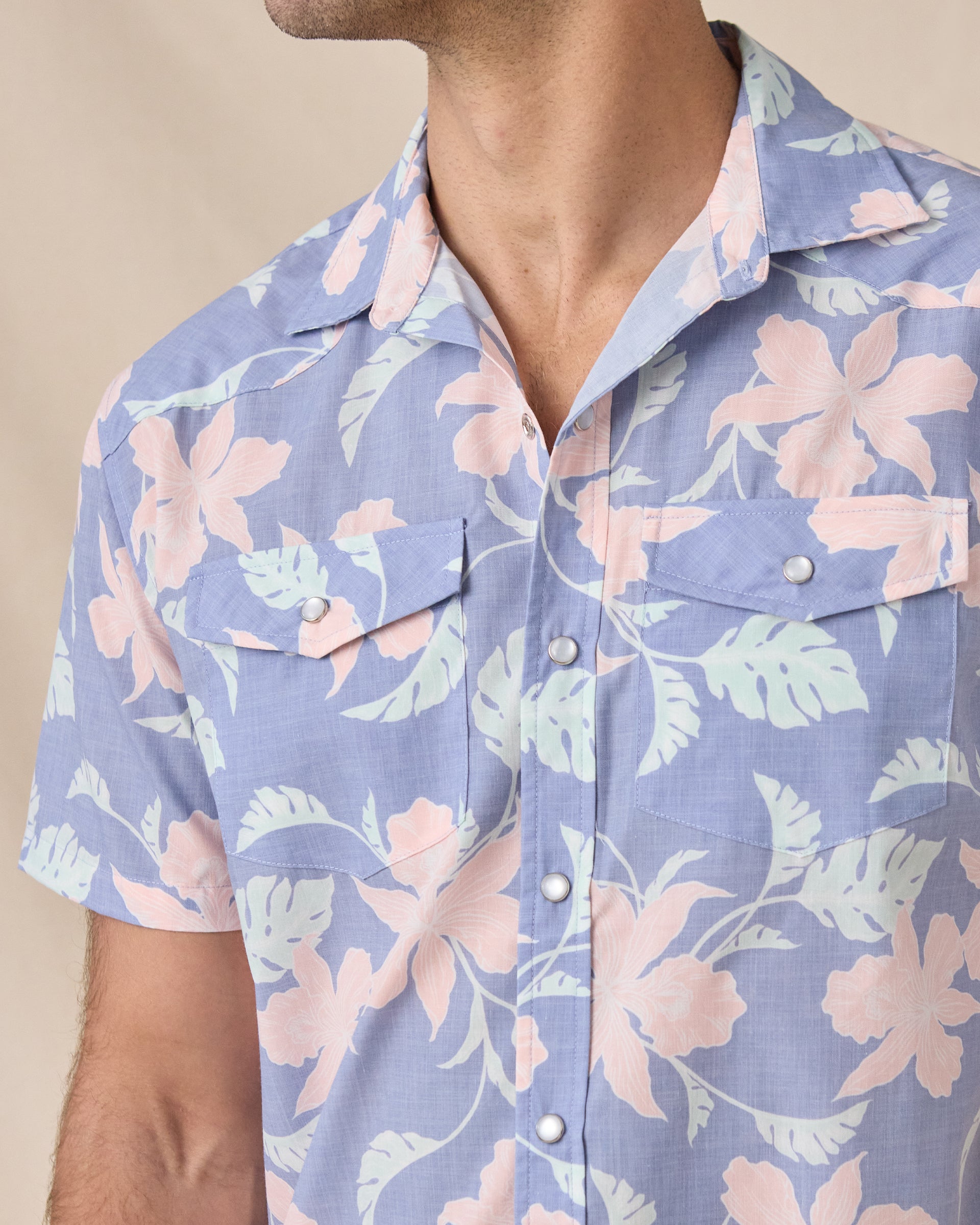Close-up of the blue floral shirt’s open collar, pearl snap front and dual chest pockets.