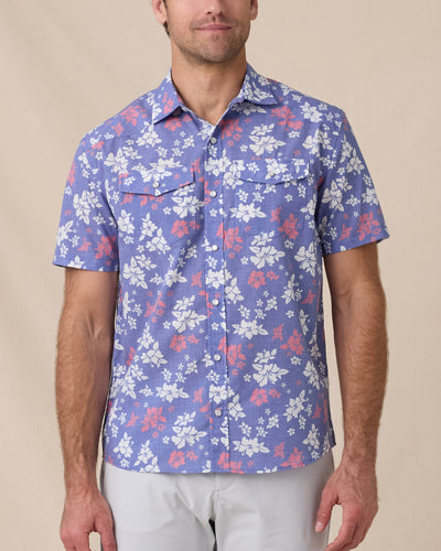 Model wearing the Paniolo Woven Shirt in Tidal Blue with a hibiscus floral print, pearl snap buttons, and dual chest pockets
