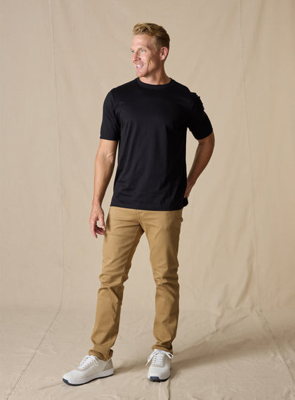Men's Luxe Tee in Black, on model full body front view featuring a black short sleeve crew neck tee paired with tan pants and white shoes